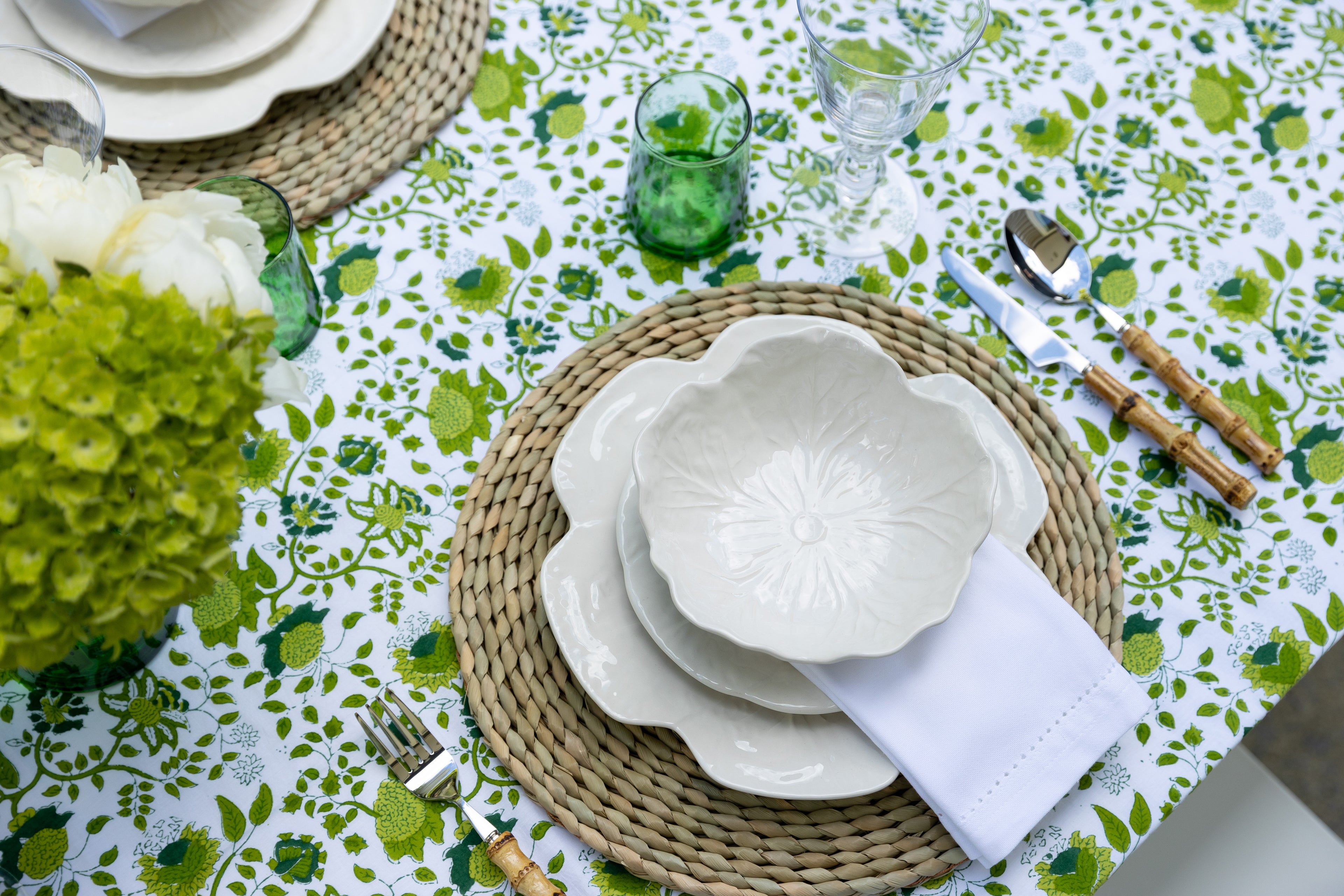 Photo of green table setting with plate, bowls , cutlery and flowers